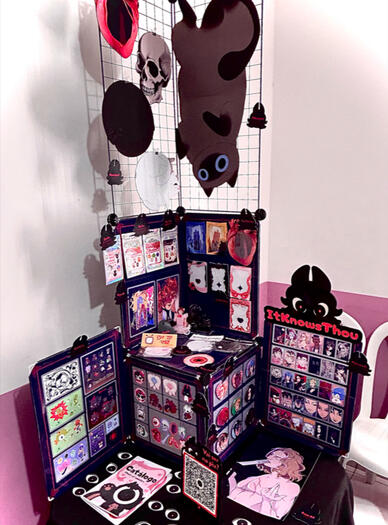 Foto de produtos expostos na mesa durante um artist alley.